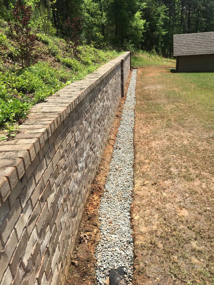 Drain stone channel along the base of a retaining wall