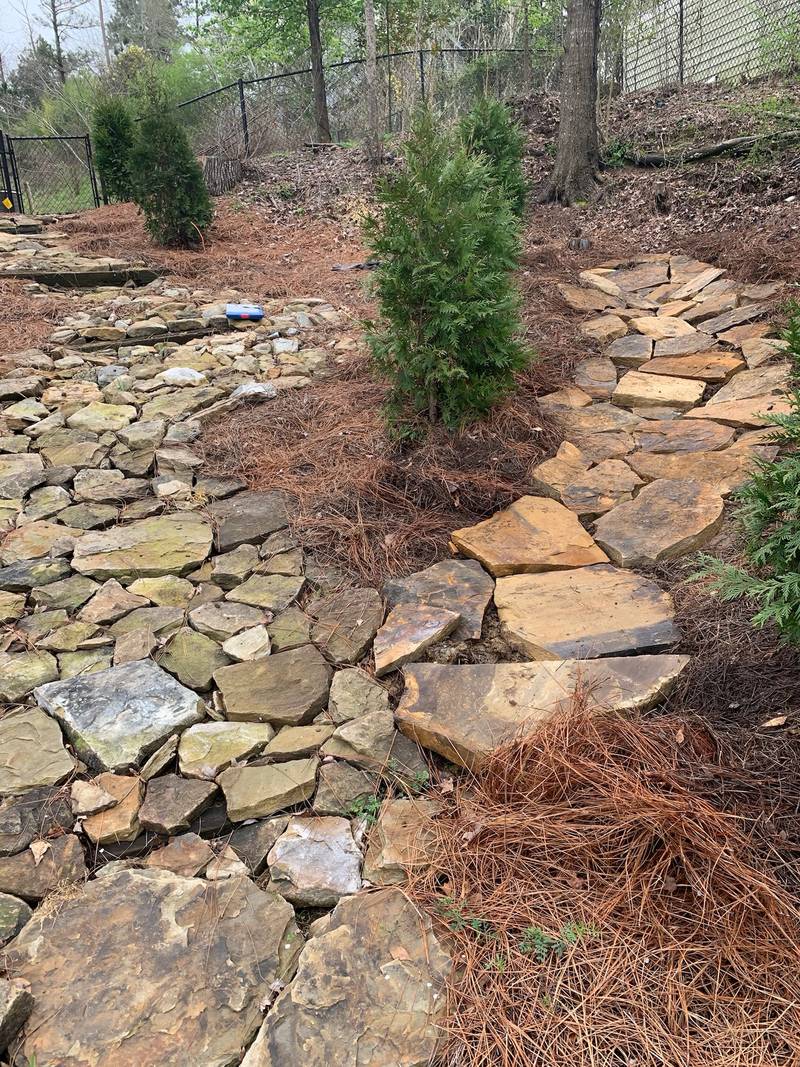 Finished dry creek bed of flagstone and river rock with evergreens