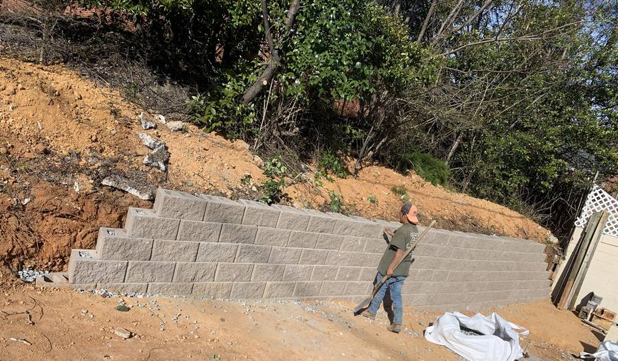 Crew building a block retaining wall on a slope
