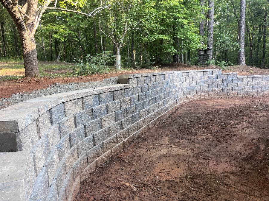 Curved block wall stepping up a wooded backyard