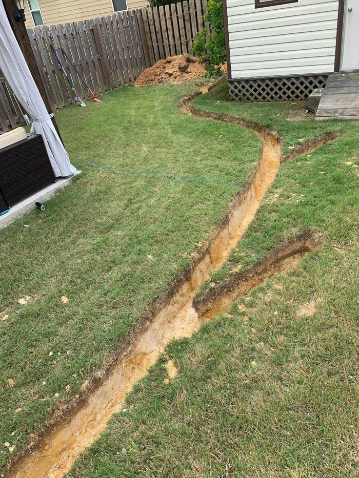 Trench cut through a lawn for a French drain