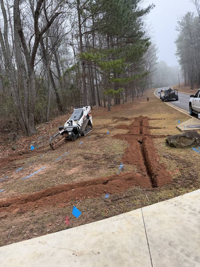 Trencher cutting irrigation lines beside a sidewalk