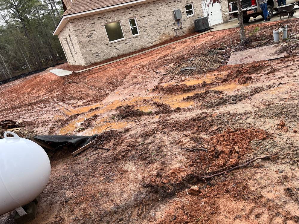 Standing water and mud on a new-construction lot before drainage work