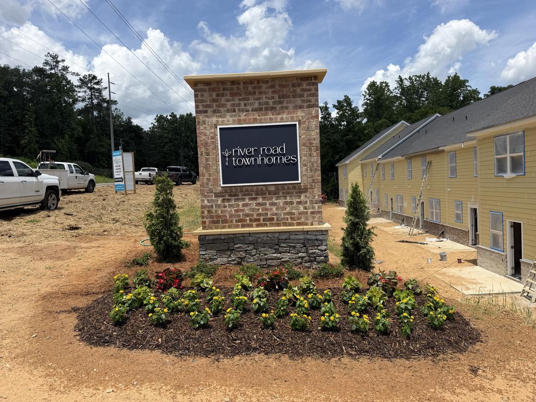 Finished entrance sign bed with arborvitae, begonias and lantana at River Road Townhomes