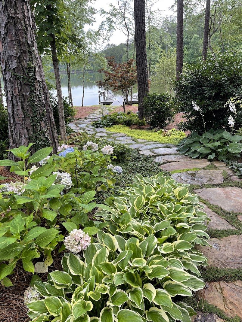 Hosta-lined flagstone path leading down to a lake dock